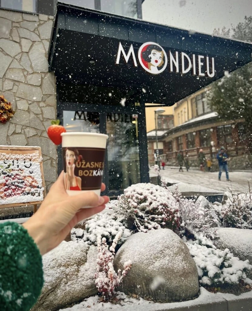 Káva Mondieu s sebou před zasněženou kavárnou ve Starém Smokovci